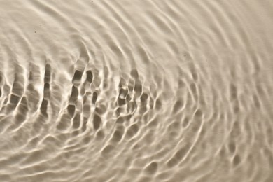 Photo of Rippled surface of clear water on beige background, top view