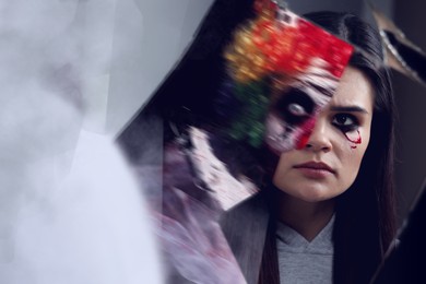 Image of Suffering from hallucinations. Woman seeing her reflection and scary clown in broken mirror