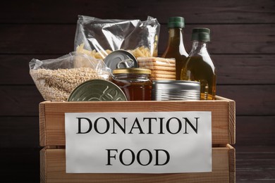 Photo of Donation crate with food on wooden background, closeup