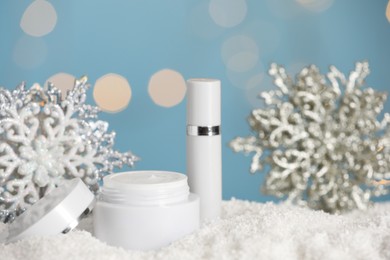 Photo of Jar of hand cream and lip balm near decorative snowflakes on snow against blurred lights. Winter skin care cosmetics