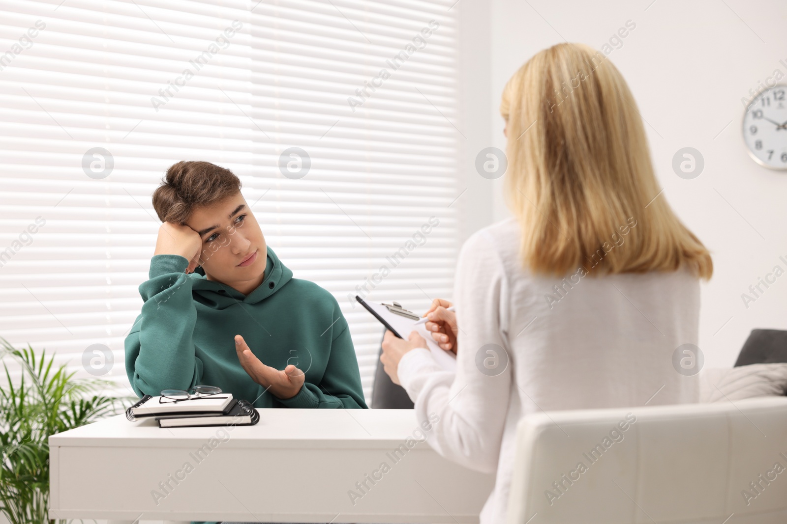 Photo of Psychologist working with teenage boy at table in office