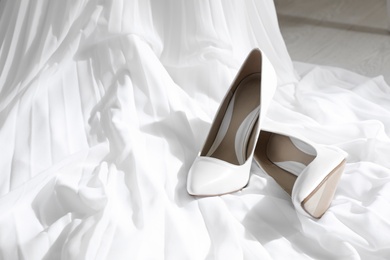 Photo of Pair of wedding high heel shoes on white fabric