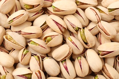 Photo of Tasty unpeeled pistachios as background, top view