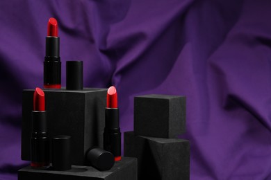 Photo of Stylish presentation of lipsticks on purple fabric. Space for text