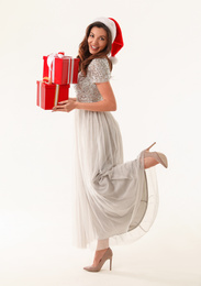 Photo of Beautiful woman wearing Santa hat with Christmas gifts on white background