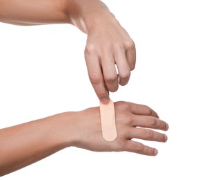 Photo of Man putting sticking plaster onto hand on white background, closeup