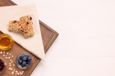 Photo of Tasty granola bars served on white wooden table, top view. Space for text