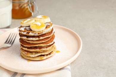 Photo of Plate of banana pancakes with honey and powdered sugar served on light table, closeup. Space for text