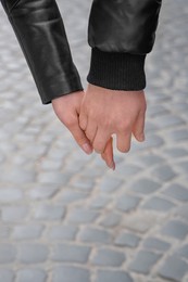 Photo of Lovely couple holding hands together outdoors, closeup. Romantic date