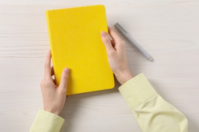 Photo of Woman with stylish notebook and pen at white wooden table, top view