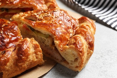 Photo of Cut delicious homemade pie on light grey table, closeup