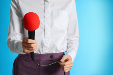 Photo of Professional journalist with microphone on light blue background, closeup