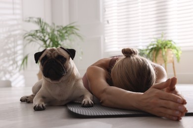 Photo of Woman with dog practicing yoga at home