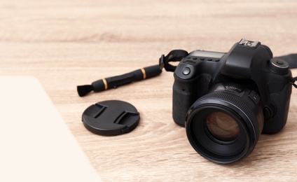Photo of Professional camera and space for text on wooden table. Photographer's equipment