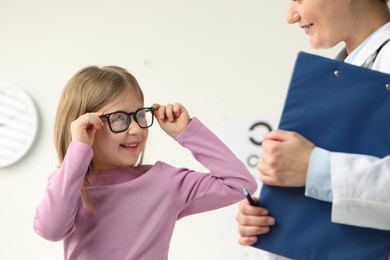 Photo of Vision testing. Little girl trying glasses at ophthalmologist office
