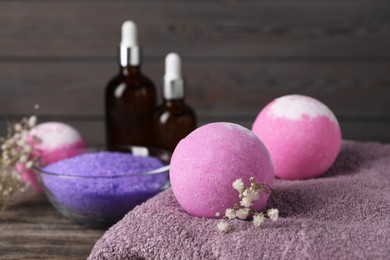 Photo of Beautiful aromatic bath bombs, gypsophila flowers and soft towel on table, closeup. Space for text