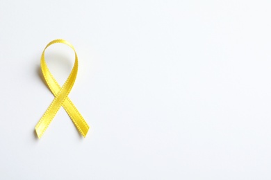 Photo of Yellow ribbon on white background, top view. Cancer awareness