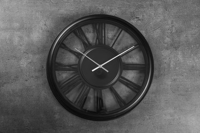 Photo of Stylish analog clock hanging on grey wall
