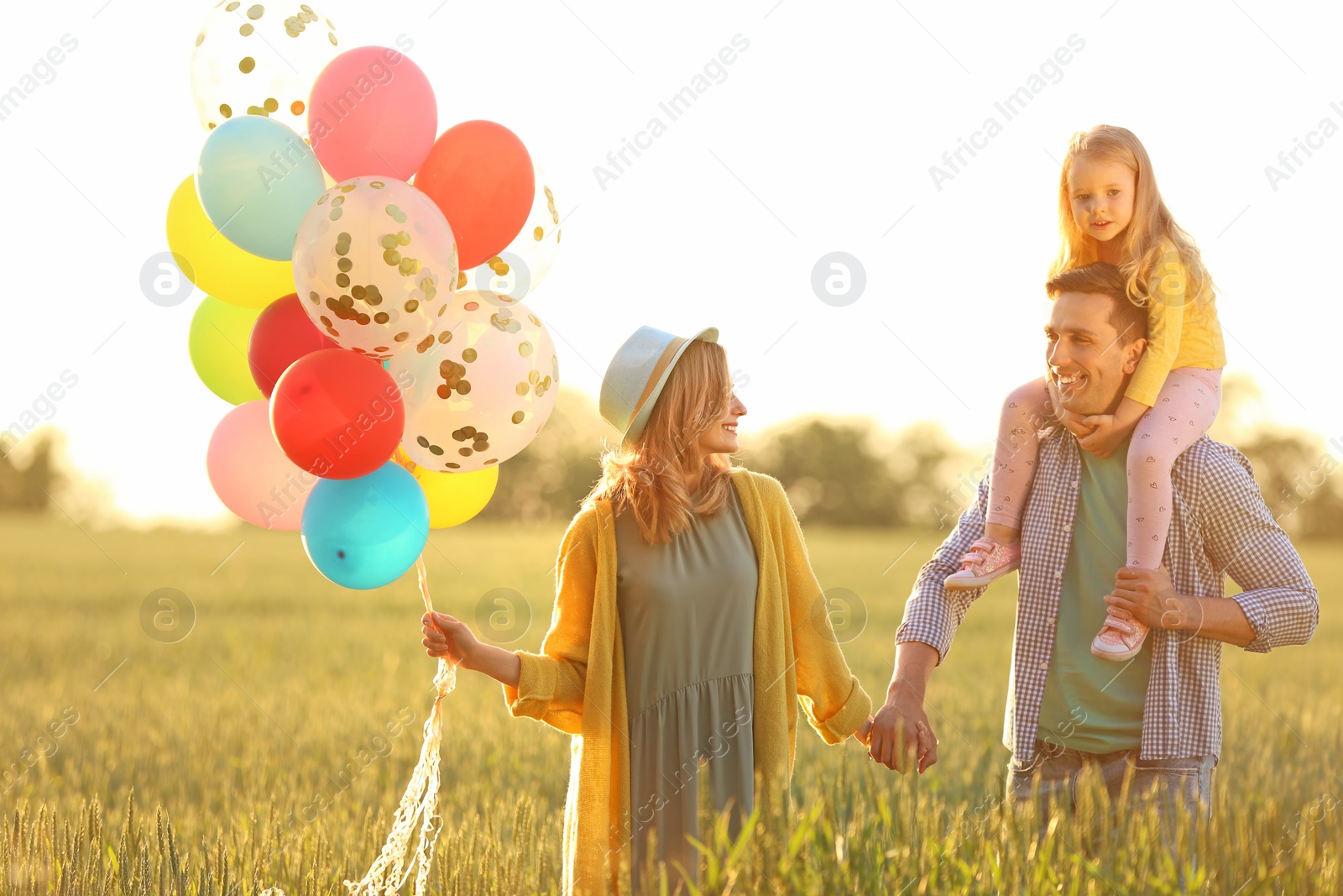 Photo of Happy family with colorful balloons in field on sunny day