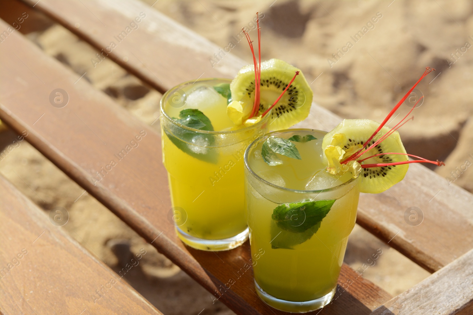Glasses of refreshing drink with kiwi and mint on wooden bench at beach Photo of Glasses of refreshing drink with kiwi and mint on wooden bench at beach