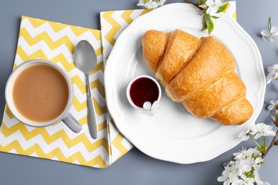 Photo of Plate with tasty croissant, jam and  cup of coffee on table, top view
