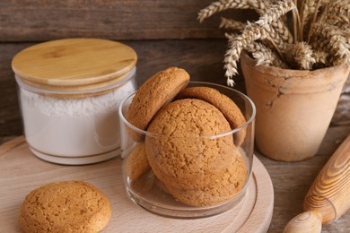 Photo of Cookies, flour and wheat spikes on wooden table