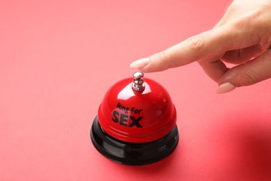 Photo of Young woman with sex bell on red background, closeup