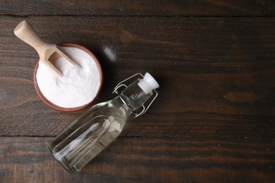 Photo of Vinegar in glass bottle and baking soda on wooden table, top view. Space for text