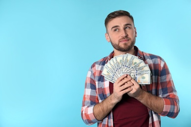 Portrait of happy young man with money on color background. Space for text