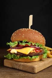 Photo of Delicious burger with beef patty and french fries on wooden table