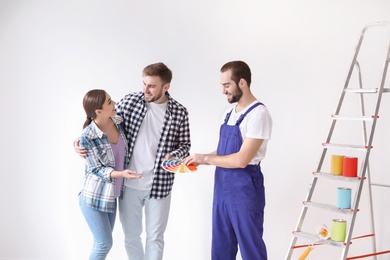 Photo of Male decorator and young couple with color palette on white background