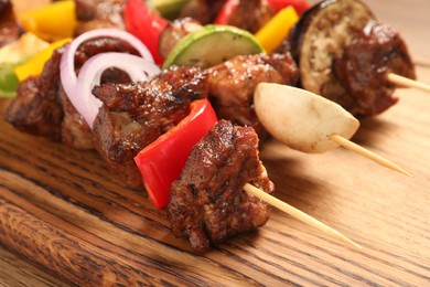 Photo of Delicious shish kebabs with vegetables on wooden table, closeup