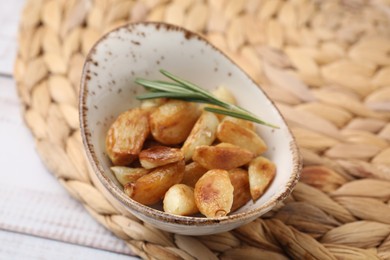 Photo of Fried garlic cloves and rosemary on table, closeup