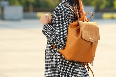 Photo of Young woman with stylish backpack on city street, closeup