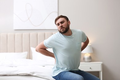 Photo of Man suffering from back pain at home. Bad posture problem