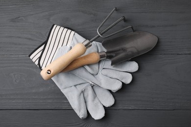 Photo of Gardening gloves, trowel and rake on grey wooden table, top view