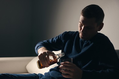 Photo of Addicted man with alcoholic drink on sofa indoors