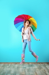 Woman with rainbow umbrella near color wall