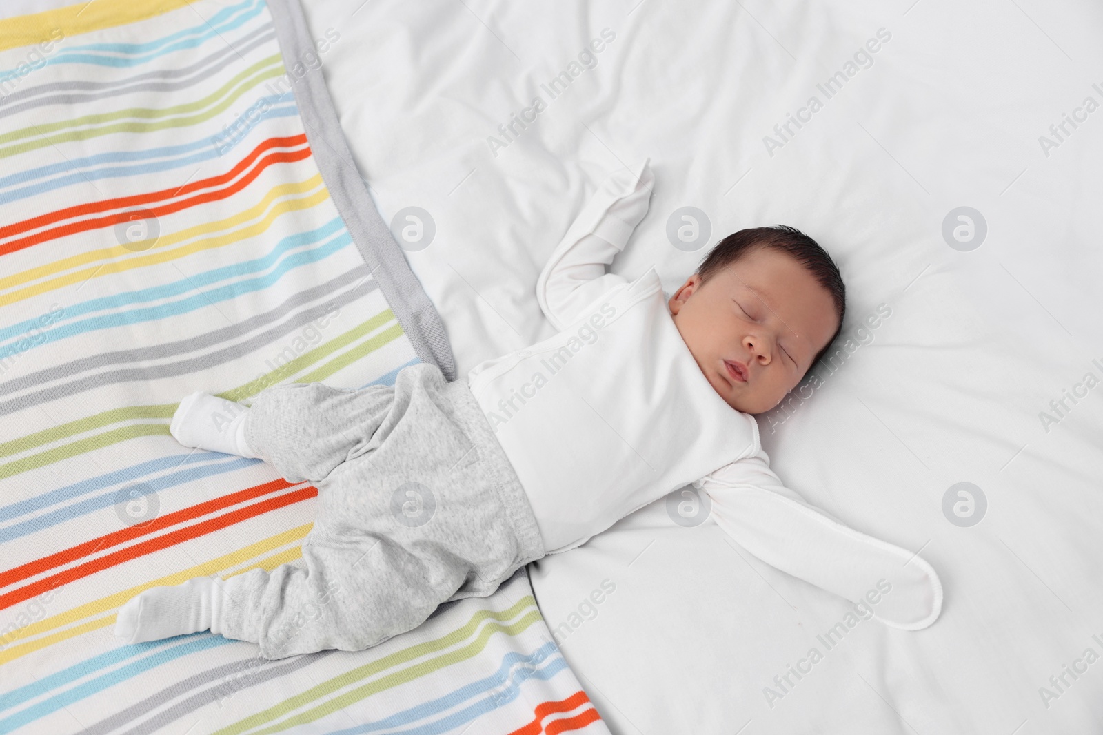 Photo of Cute newborn baby sleeping on soft bed, top view