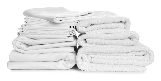 Stacks of towels and bed sheets on white background