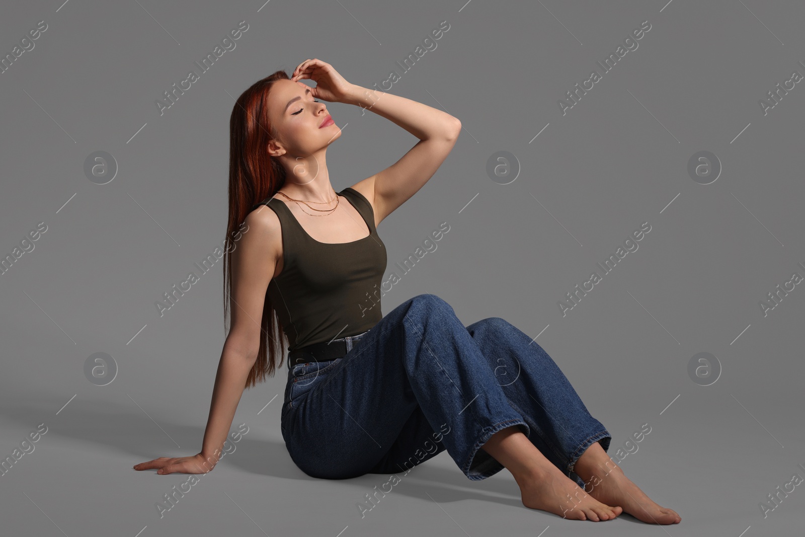 Photo of Beautiful young woman sitting on gray background