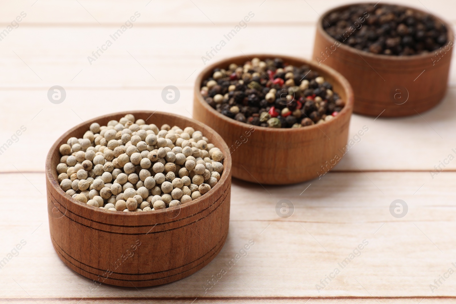 Photo of Aromatic spices. Different peppers in bowls on wooden table