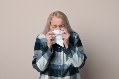 Sick mature woman on beige background. Dangerous virus