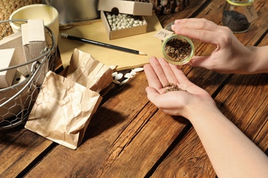 Woman with vegetable seeds at wooden table, closeup