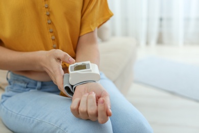 Woman checking blood pressure at home, closeup with space for text. Cardiology concept