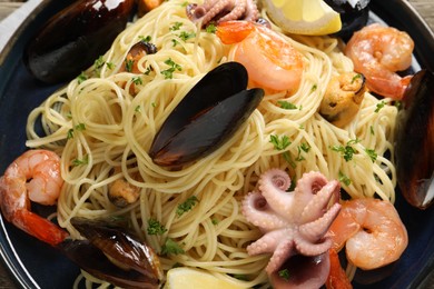 Photo of Delicious spaghetti with seafood on plate, top view