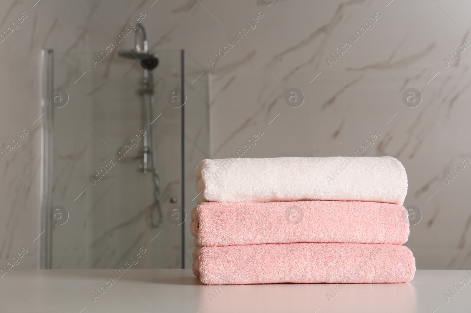 Photo of Stack of clean towels on table in bathroom. Space for text