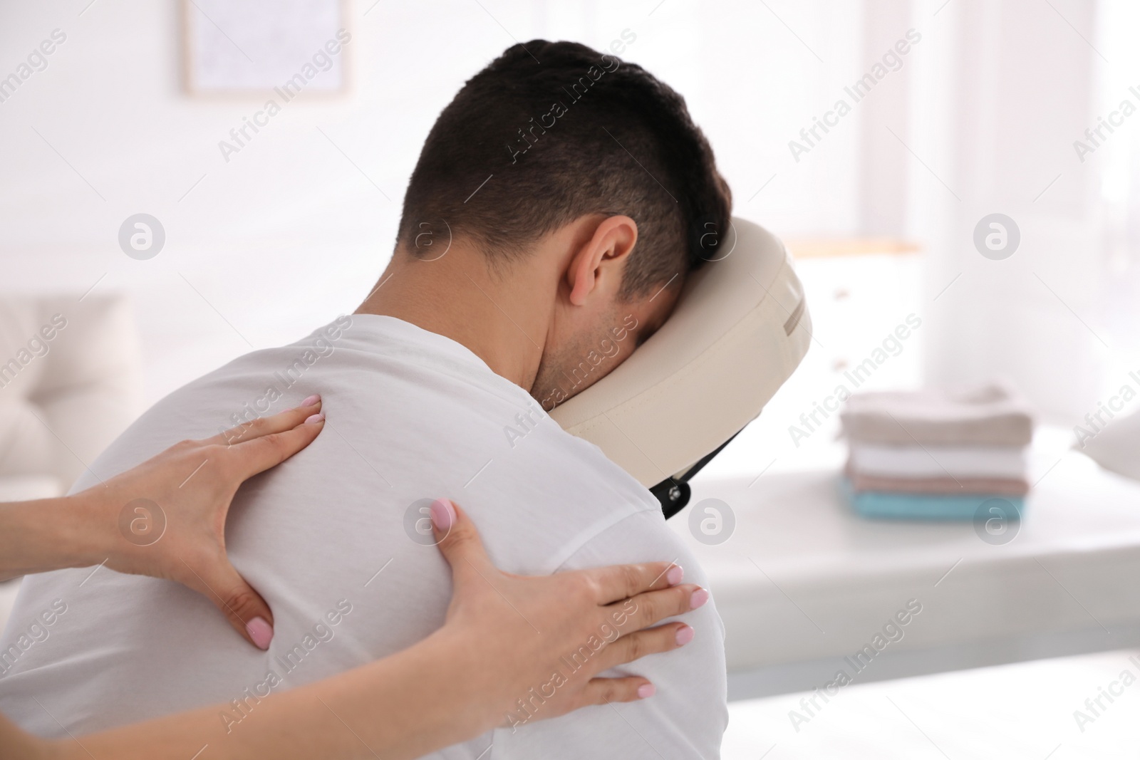 Photo of Man receiving massage in modern chair indoors