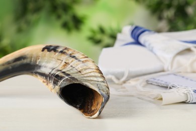 Photo of Shofar and Tallit on white wooden table, space for text. Rosh Hashanah holiday attributes