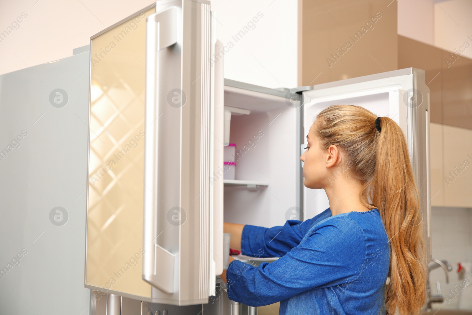 Photo of Young woman choosing food in refrigerator at home